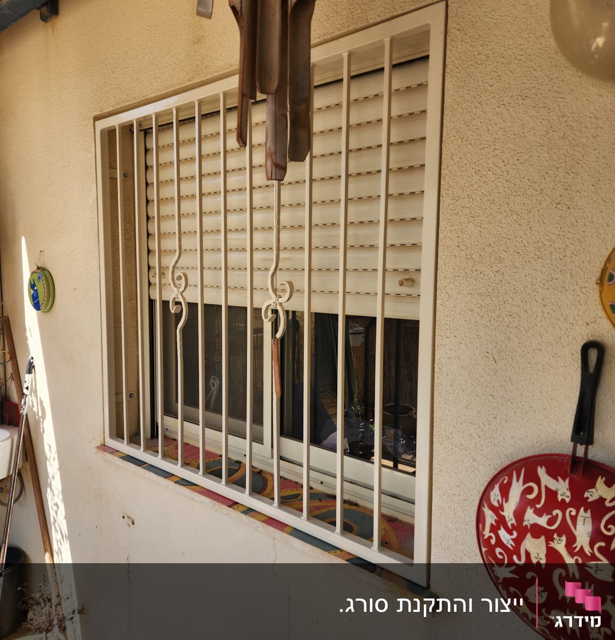 חלון עם סורגים לבנים ותריסים סגורים